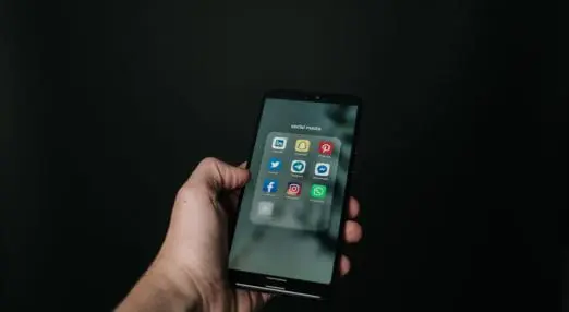 a smart phone in a hand showing social media icons