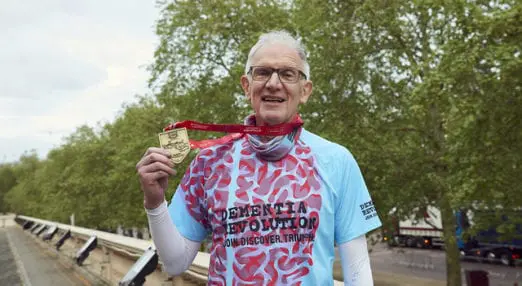 Man wearing a dementia revolution tshirt holding a medal