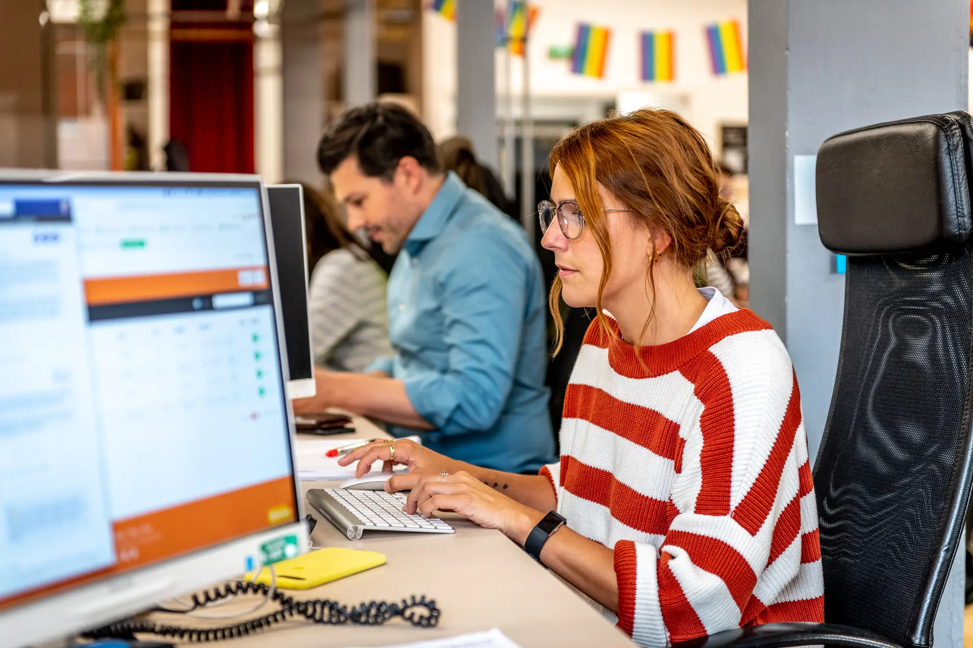 woman and man sat at desk working on computers
