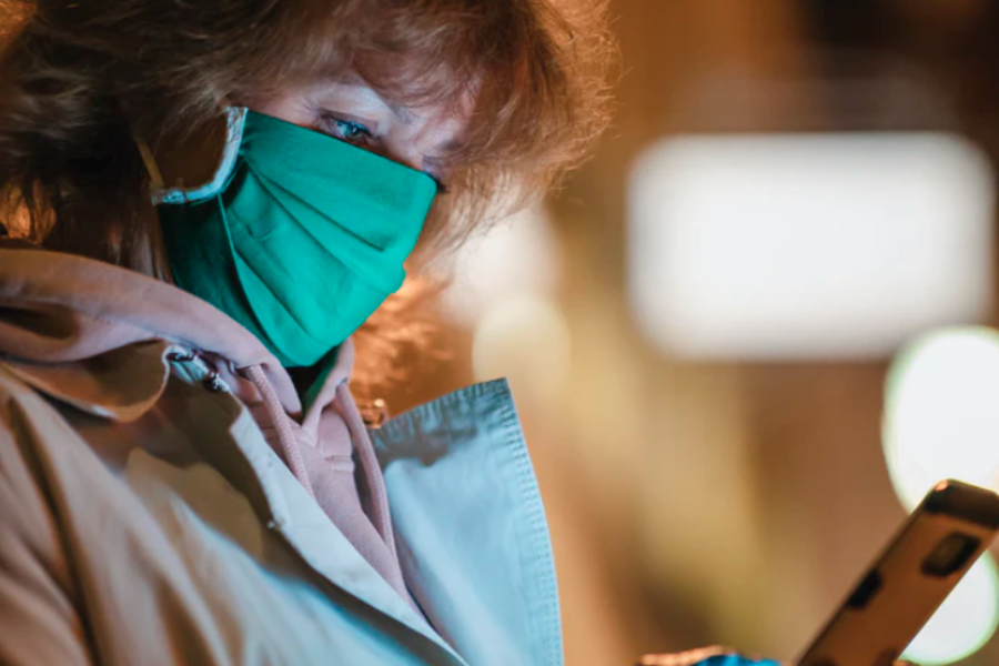 a woman wears a mask while on her mobile phone