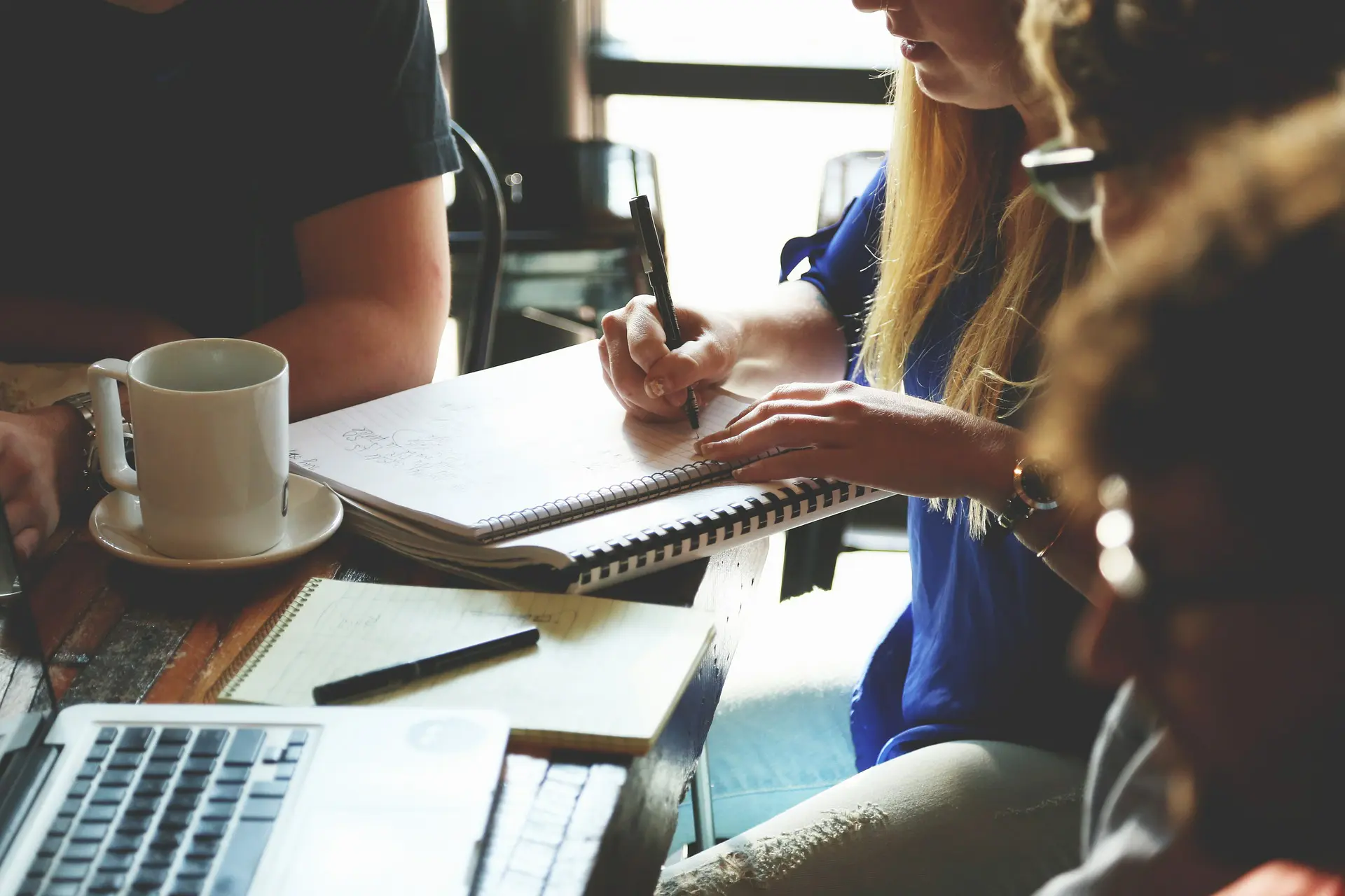 group sits round a table with a laptop and a notepad