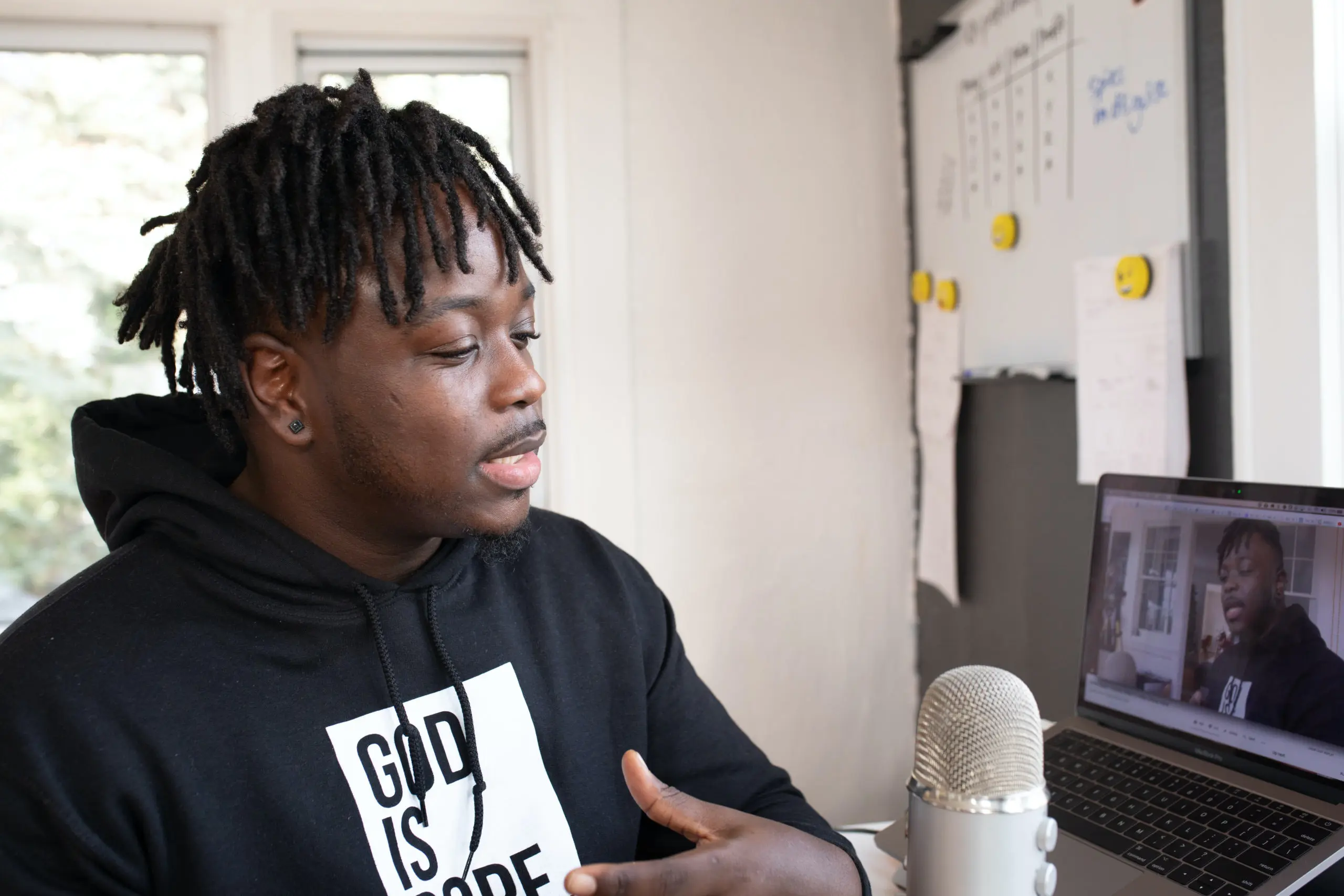 man stands by a laptop with a microphone