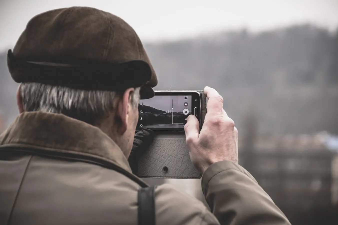 back of man's head taking photo with smartphone