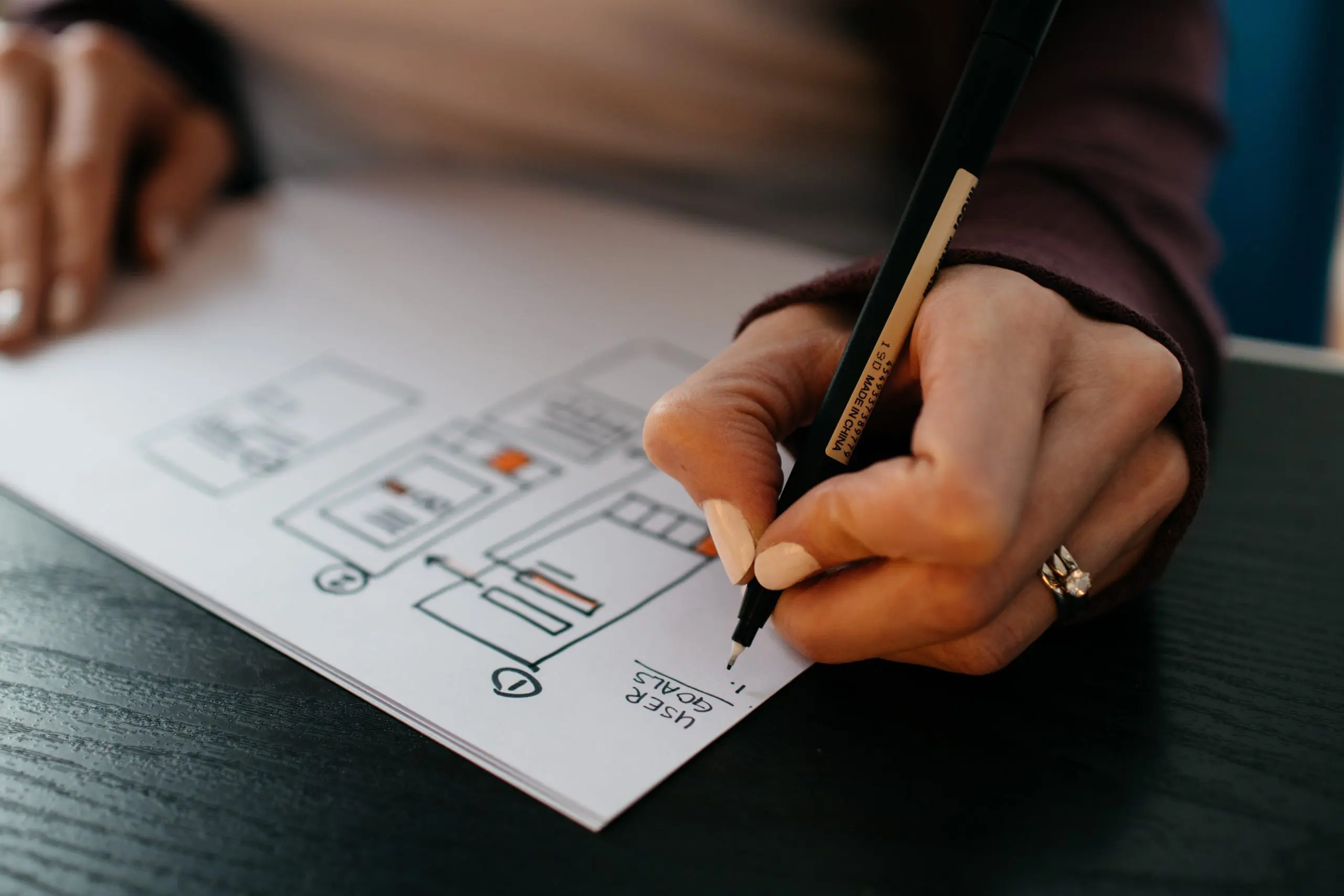 woman drawing a wireframe and writing down user goals which are often assumed in speculative design
