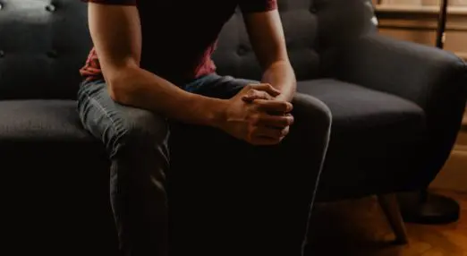 person sat on a couch holding their hands together