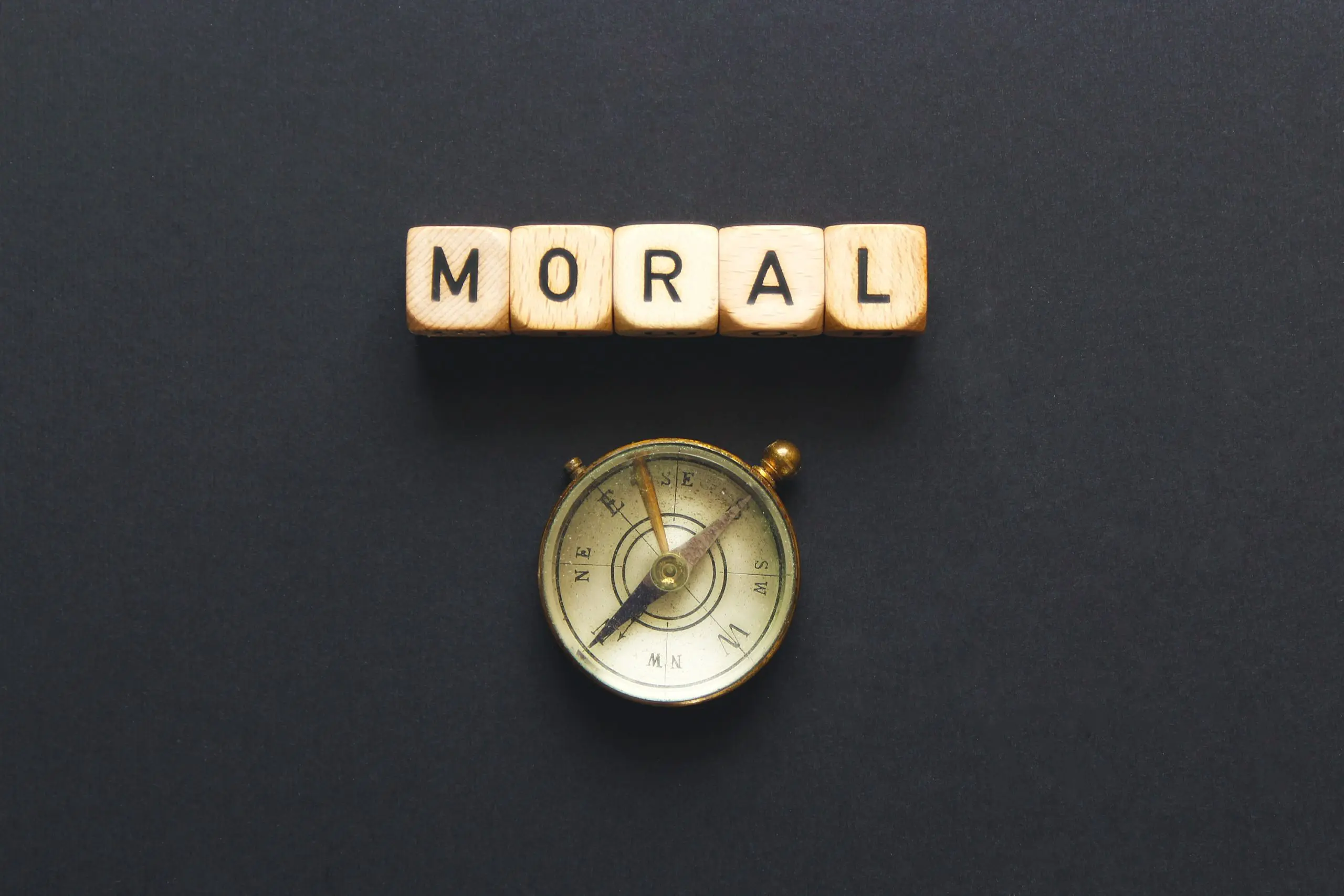 square letters that spell out the word Moral, above a compass