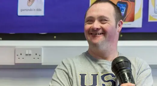 a man at the Leonard Cheshire centre smiling with a microphone in his hand