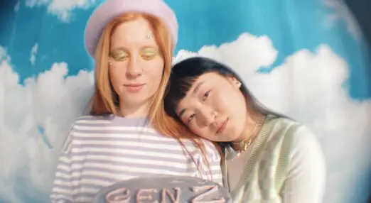 a fisheye lens picture of two girls holding a purple cake that has gen z piped on it