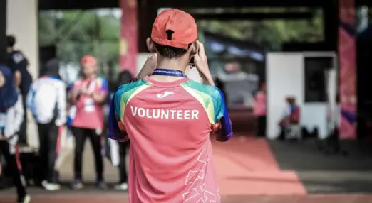 a person in a red hat in a shirt that reads volunteer