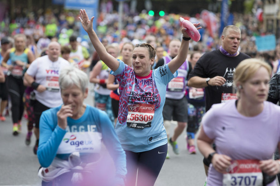 Woman running with hands up at ondon Marathon