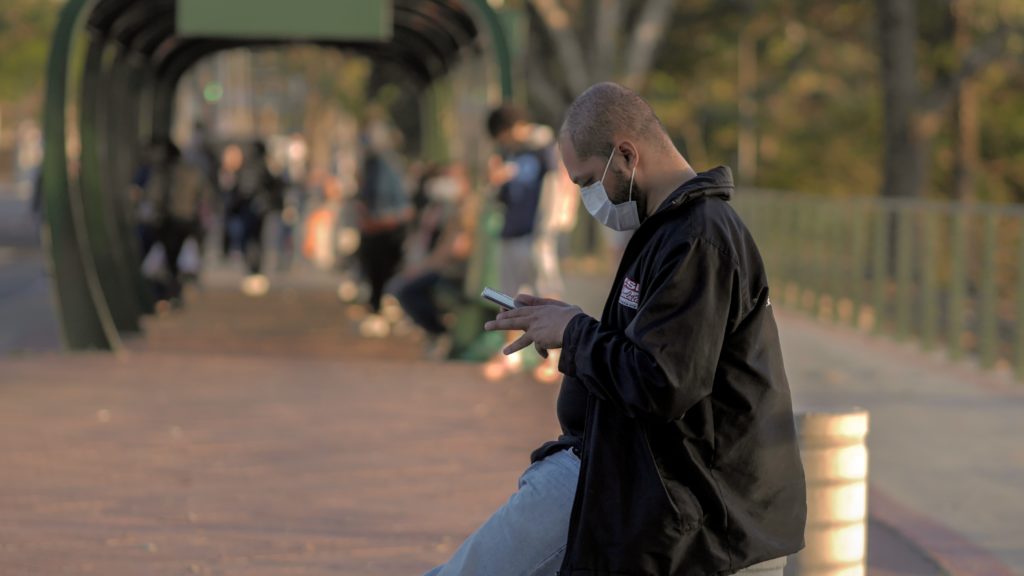 man texting while wearing a surgical mask