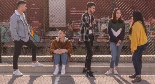 five teenagers stood inside a basketball court talking