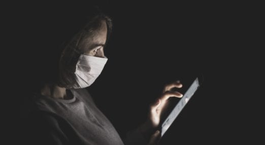 woman using smartphone in the dark wearing face mask