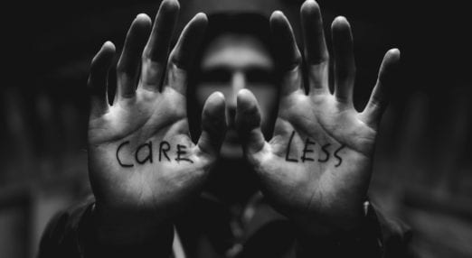 photo of man with 'care less' written on each hand