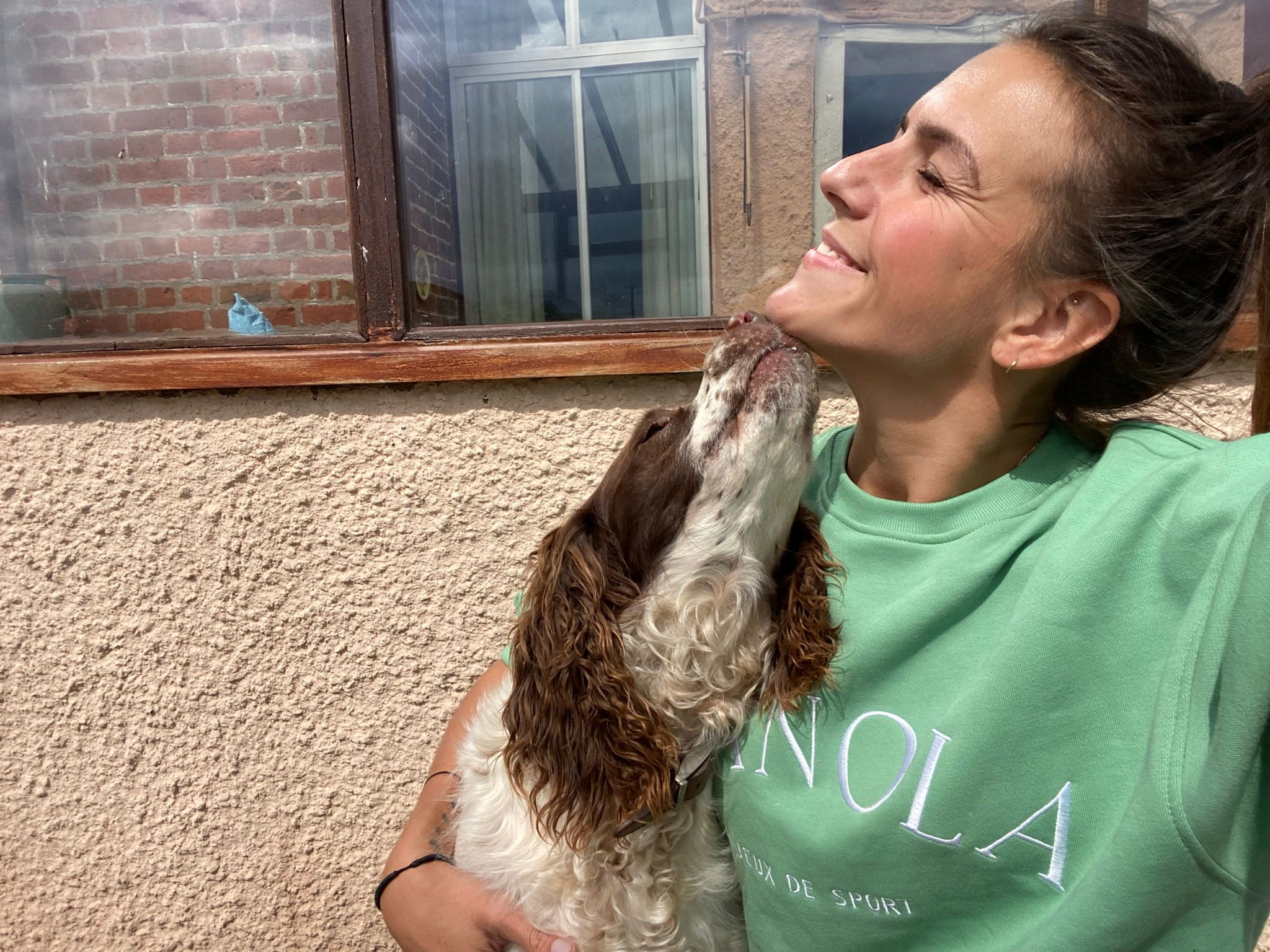 Selfie of a spaniel licking the chin of a smiling girl