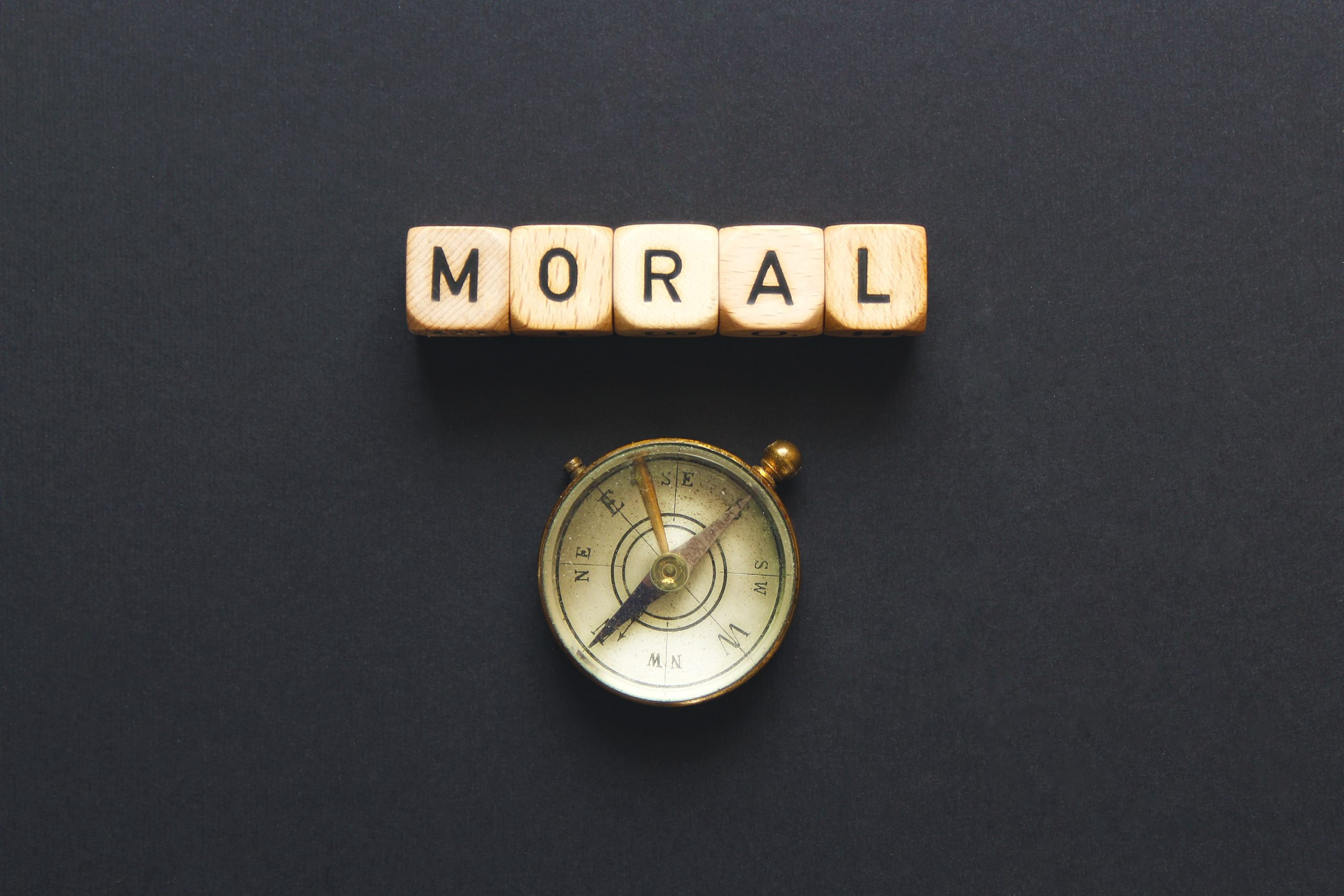 square letters that spell out the word Moral, above a compass
