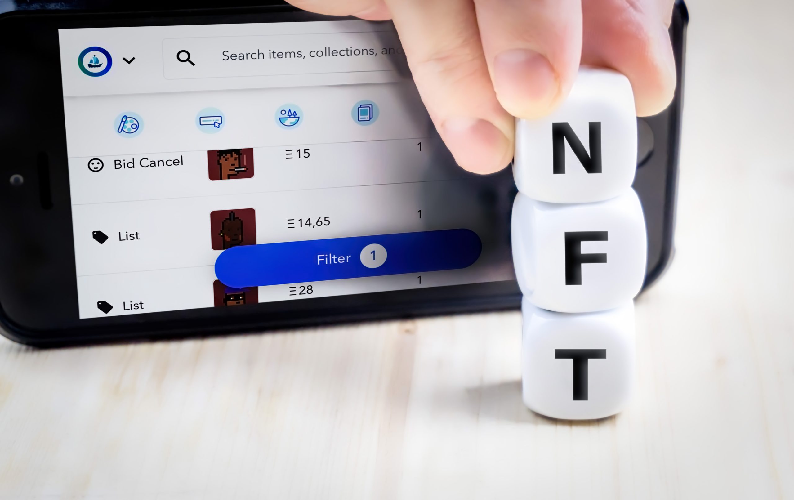 blocks spelling out 'NFT' in front of a screen showing an NFT trading platform
