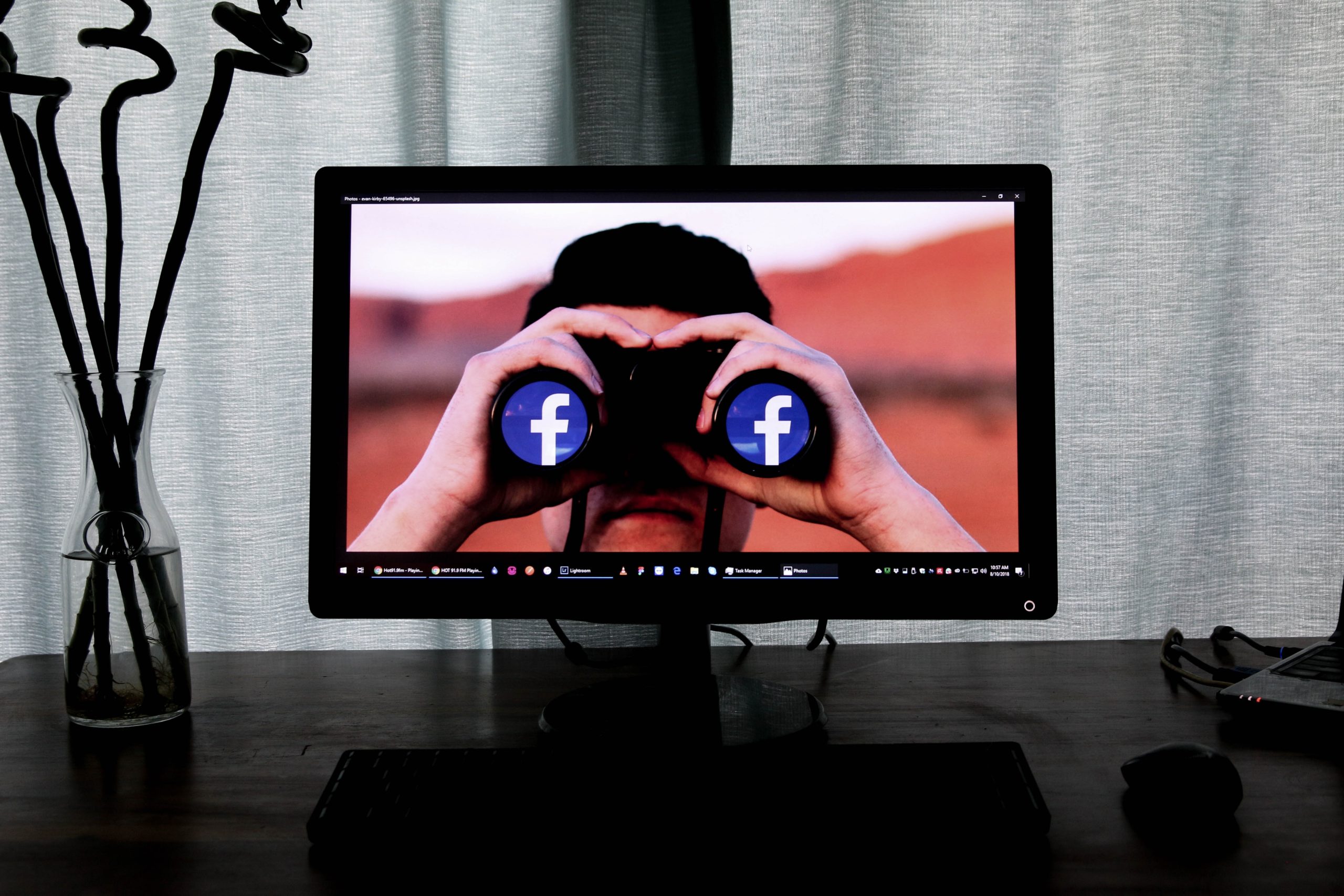 a computer screen showing a man holding binoculars with the facebook logo