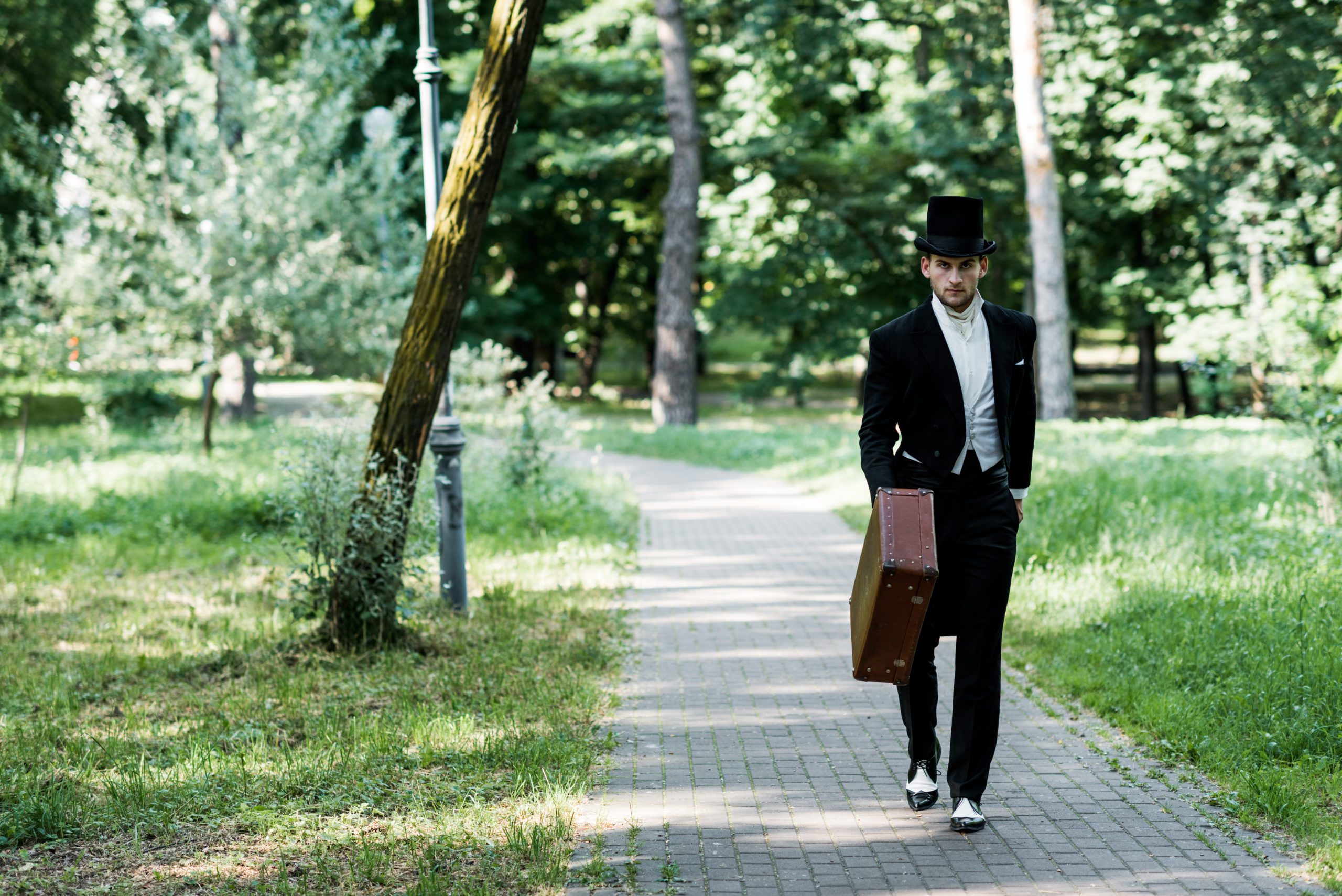 man dressed up in victorian attire walking through a park