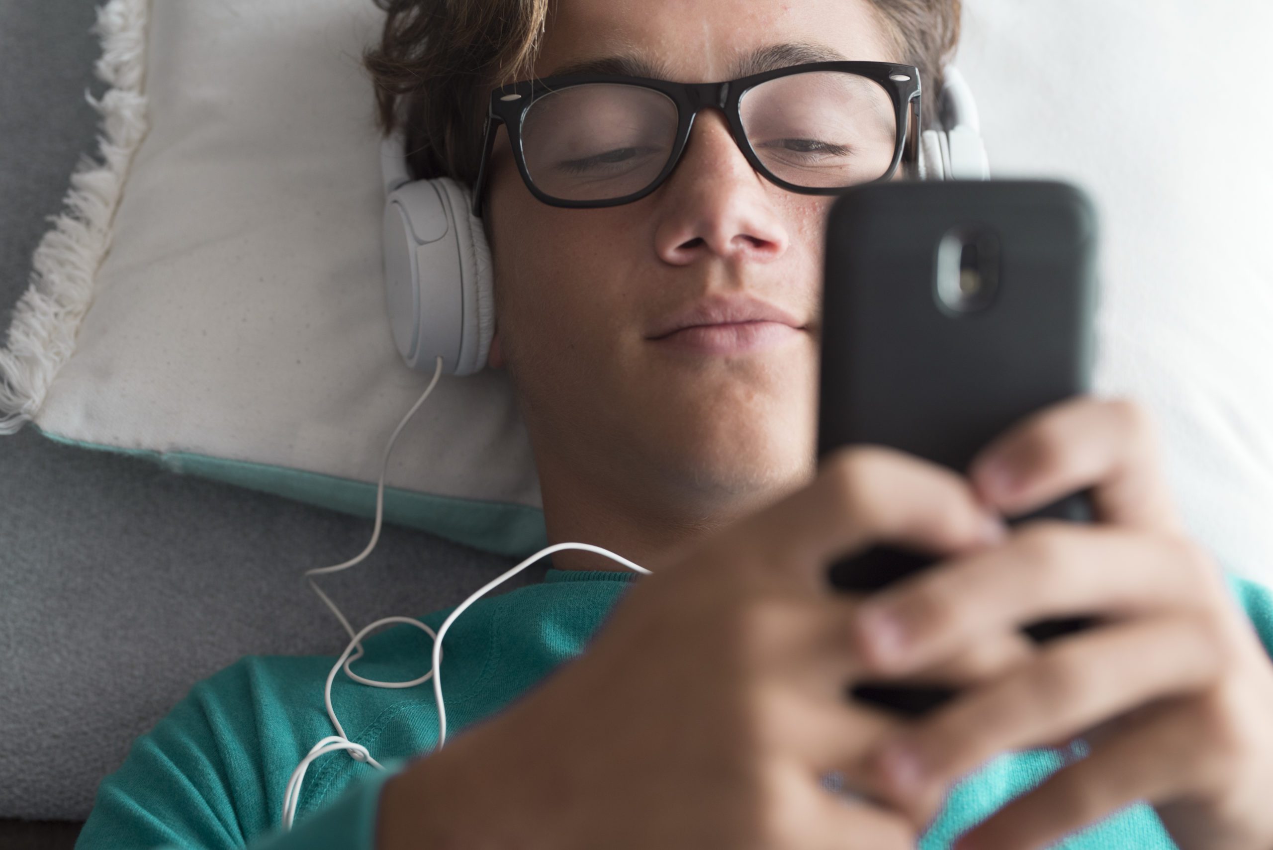 young boy with headphones on looking at his phone