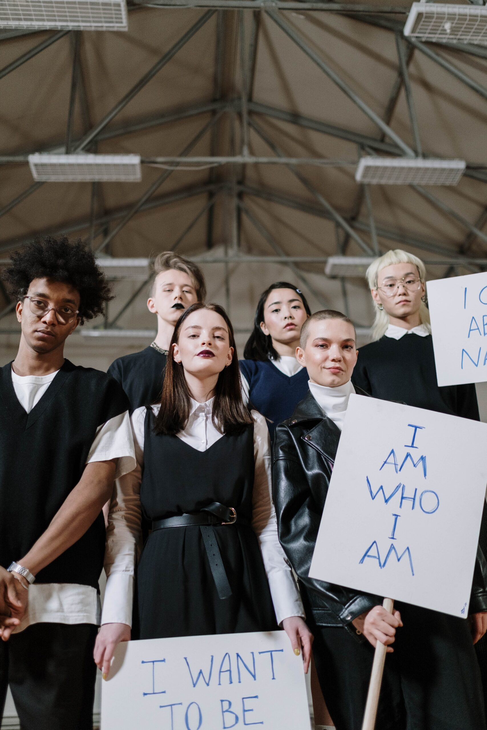 a group of gen z young adults in black stnading with signs