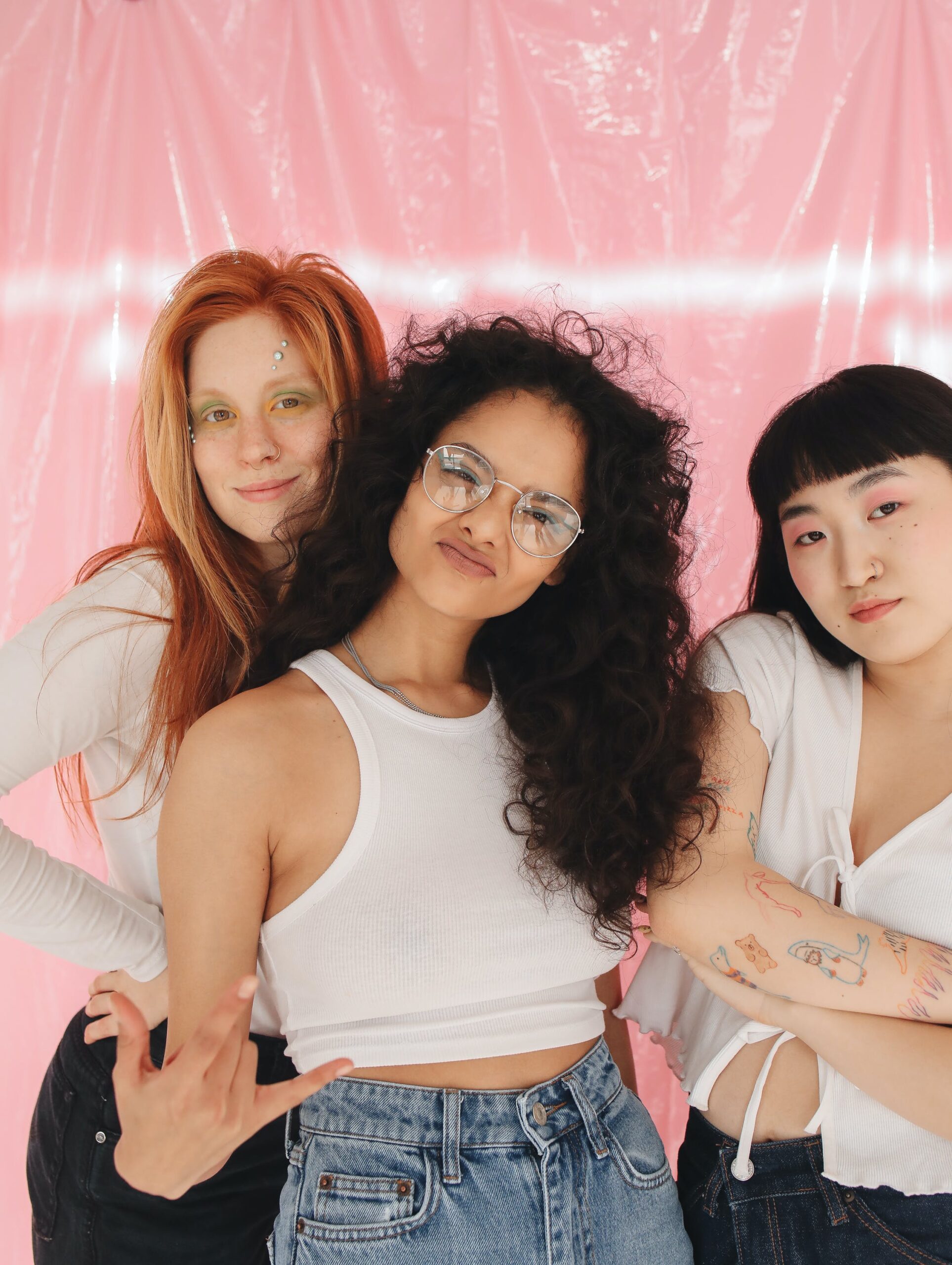 a group of gen z girls posing in front of a pink background