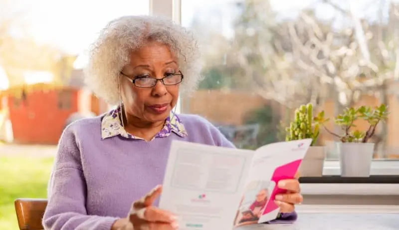 An elderly woman reading a Dementia UK brochure